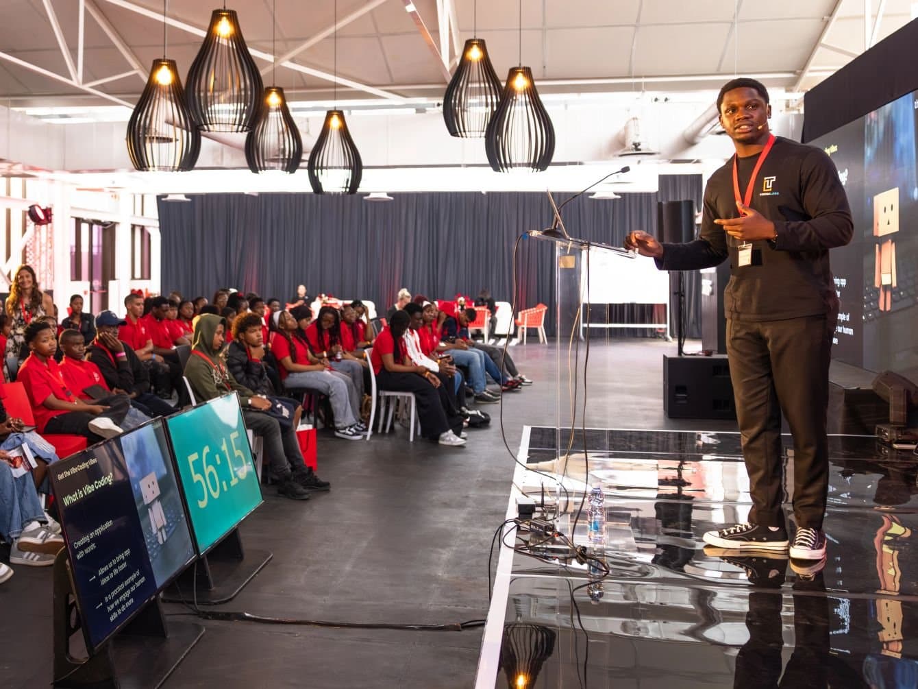 David on stage leading a live vibe coding workshop for a full hall of scholars